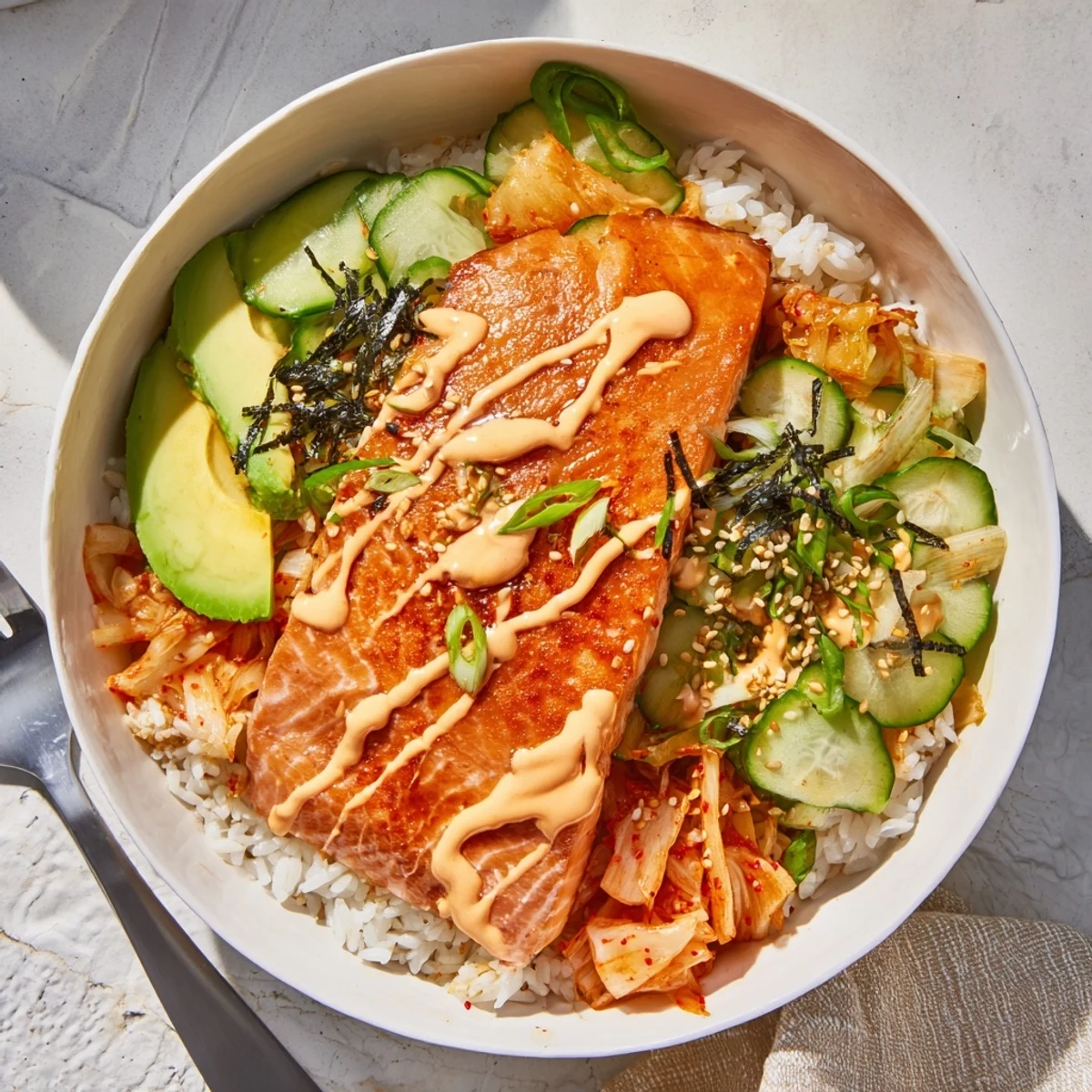 Crispy Salmon Rice Bowl topped with spicy mayo, kimchi, and fresh avocado slices.  