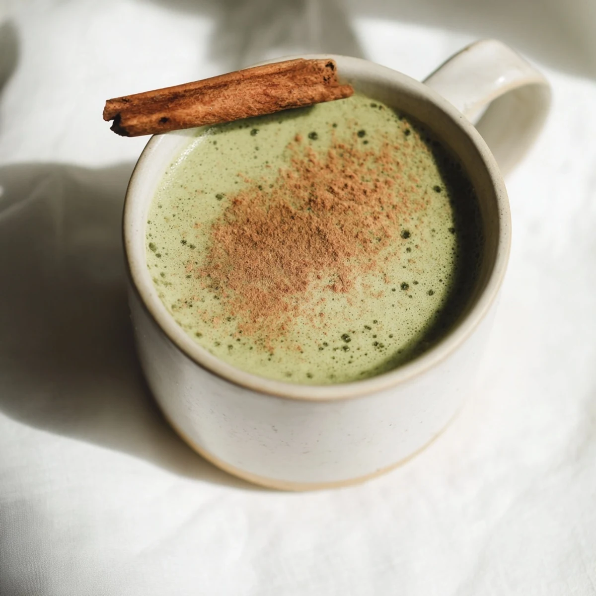 A warm mug of Maple Cinnamon Gingerbread Matcha Oat Latte, perfect for a chilly morning.
