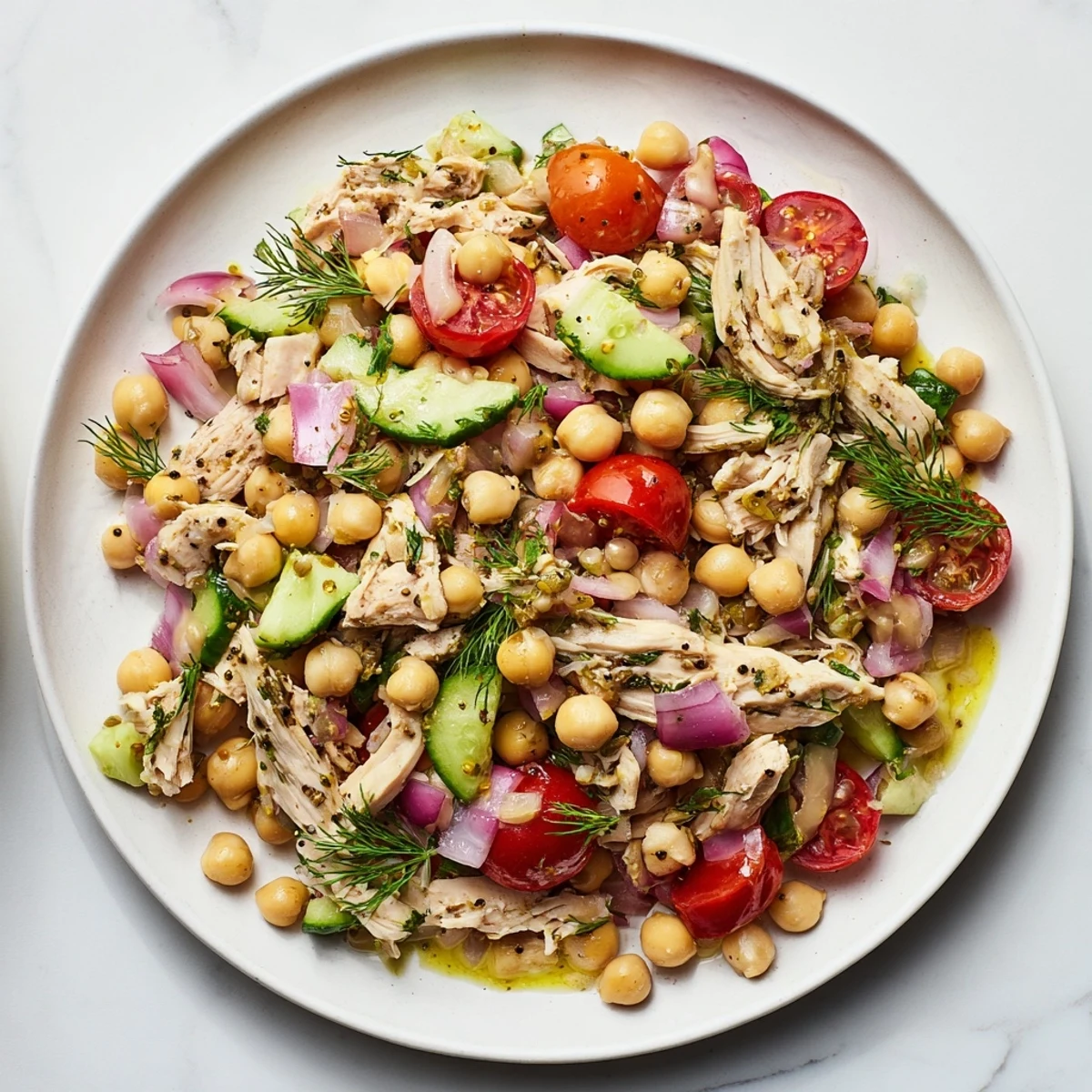 A colorful bowl of Dense Bean Salad with Lemon-Dill Chicken offers a fresh, Mediterranean-inspired meal, ready to serve cold.