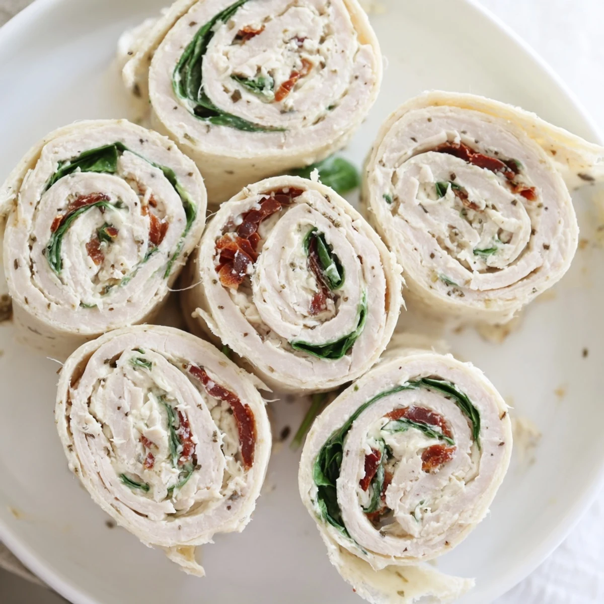 Close-up of savory sun-dried tomato turkey roll-ups, ready to eat, with visible fresh spinach.