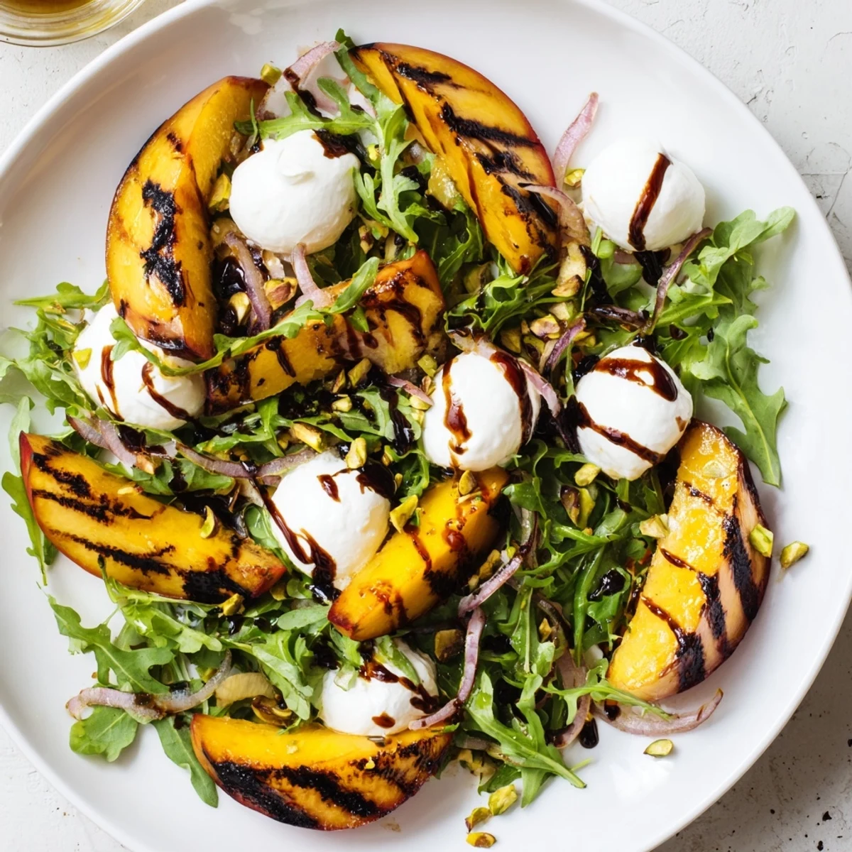 Close-up of a delicious grilled peach salad topped with creamy burrata cheese.