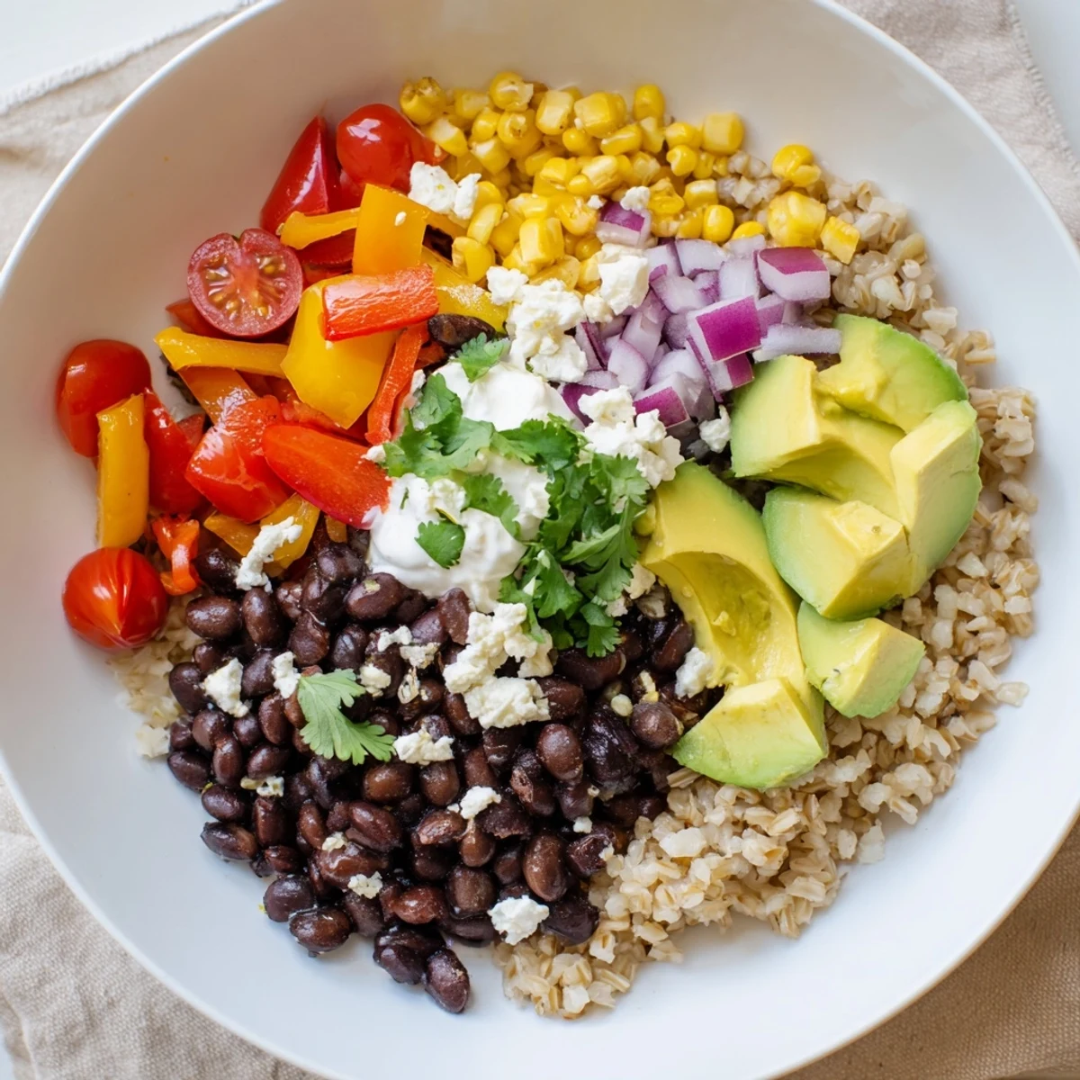 Brown rice burrito bowl with seasoned black beans, fresh veggies, and creamy toppings.