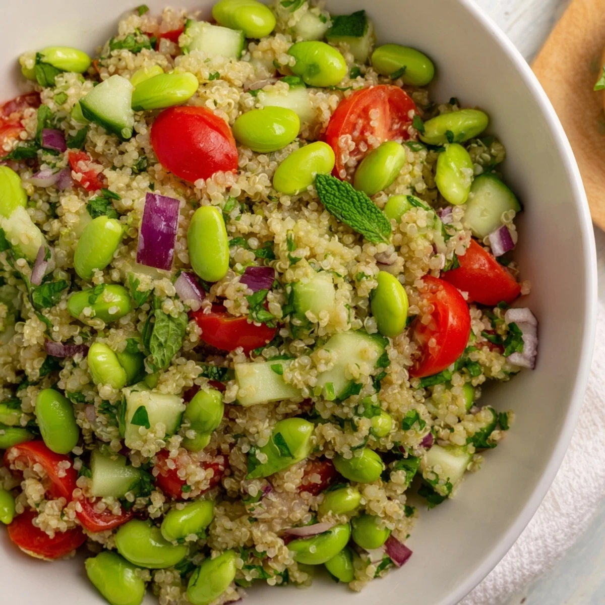 Colorful bowl of Edamame and Quinoa Salad with finely chopped red onion and fresh mint, ready to serve as a light vegetarian side dish.