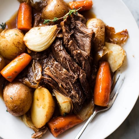 Hearty Sunday Pot Roast surrounded by vibrant roasted carrots and potatoes.  