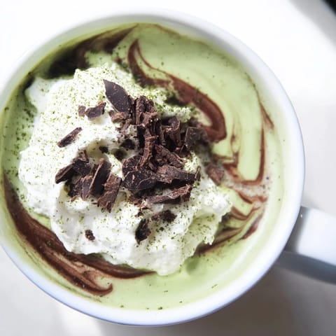 Steaming hot Matcha Hot Cocoa Protein Mug topped with whipped cream, perfect for a cozy afternoon.