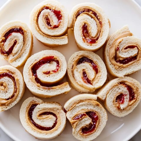 Quartered PB&J pinwheel rolls, a colorful snack, ready to eat with peanut butter and jelly swirls.