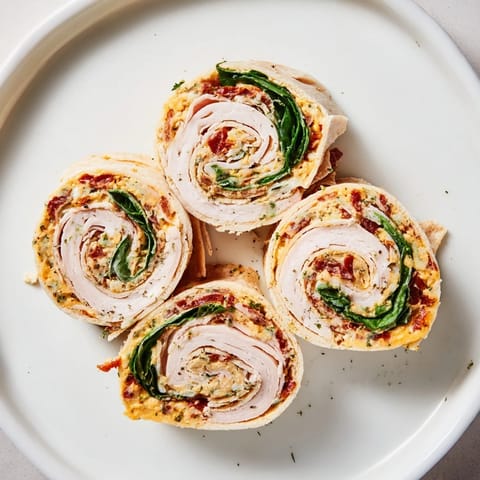 Close-up of savory sun-dried tomato turkey roll-ups, ready to eat, with visible fresh spinach.