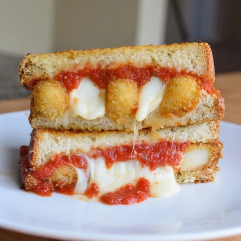 Crispy Mozzarella Stick Grilled Cheese, a melty, cheesy sandwich on a plate with marinara for dipping.