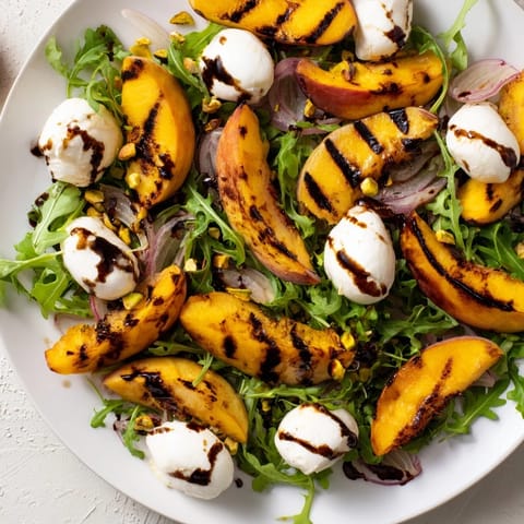 Vibrant grilled peach salad showcasing juicy peaches, peppery arugula, and aged balsamic glaze.