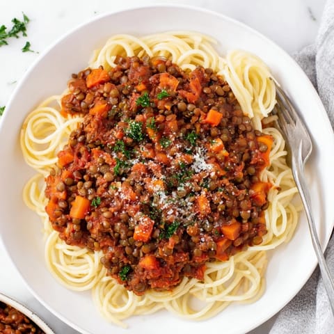 Rich, hearty Lentil Bolognese served in a rustic bowl, with a side of garlic bread for dipping.