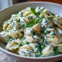 Creamy lemon ricotta pasta with vibrant green peas and fresh mint, ready to serve.